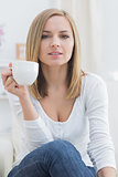 Young woman with coffee cup sitting on couch