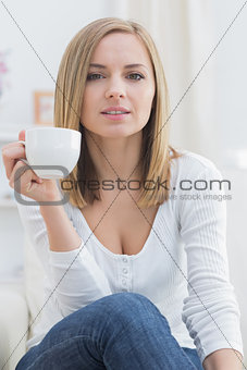 Young woman with coffee cup sitting on couch