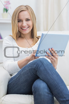 Portrait of casual happy woman using digital tablet on sofa