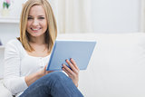 Portrait of casual young woman using digital tablet on sofa