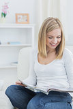 Happy casual woman reading magazine at home