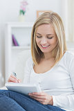 Relaxed young woman writing in notepad at home