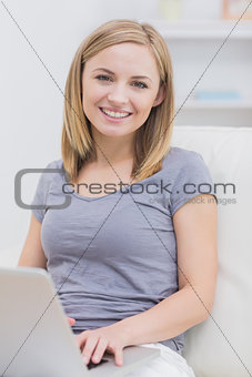 Portrait of happy casual woman using laptop on sofa