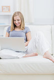 Relaxed happy woman using laptop on sofa