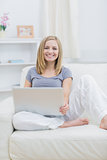 Portrait of relaxed happy woman using laptop on sofa