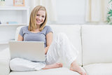 Portrait of relaxed happy woman using laptop on sofa