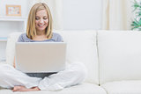 Relaxed happy woman using laptop on sofa