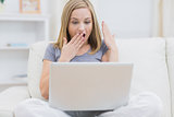 Surprised casual woman using laptop at home