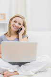 Portrait of casual woman using laptop and cellphone at home