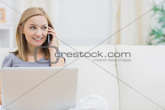 Casual woman using laptop and cellphone at home