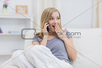 Casual surprised woman using cellphone at home