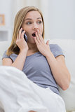Casual shocked woman using cellphone at home