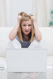 Portrait of frustrated casual woman with laptop at home