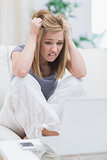 Frustrated casual young woman looking at laptop screen