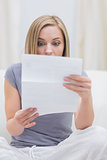 Casual woman reading letter in living room