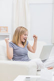 Excited casual woman with laptop at home