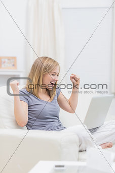 Excited casual woman with laptop at home