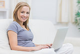 Portrait of happy casual woman using laptop at home