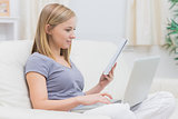 Casual woman using laptop and holding book in living room