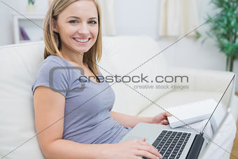 Casual woman with laptop and book in living room