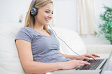 Woman listening music through headphones while using laptop