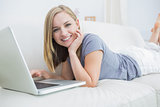 Young woman lying on couch and using laptop