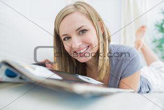 Portrait of casual woman with magazine lying on couch
