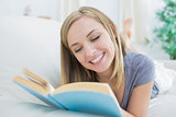 Happy woman reading book lying on couch