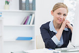 Smiling confident business woman with computer at office desk