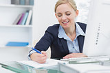 Business woman writing notes at desk in office
