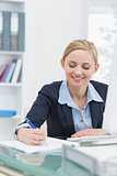 Business woman writing notes at office desk