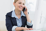 Happy business woman using computer while on call at desk