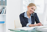Portrait of business woman using phone and computer at desk
