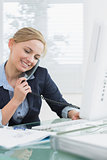 Female executive using landline phone and computer at desk