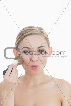 Portrait of young woman putting on makeup