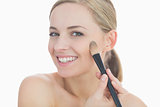 Portrait of smiling young woman putting on makeup