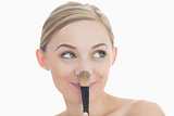 Closeup of smiling young woman with makeup brush