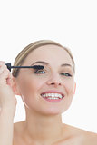 Closeup portrait of young woman applying mascara to her eye