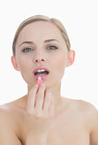 Closeup portrait of young woman applying lipgloss