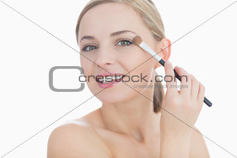 Closeup portrait of young woman applying eye shadow