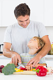 Father and son looking at each other as they are chopping vegetables