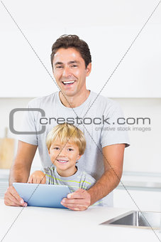 Laughing father and son using tablet