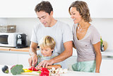 Mother watching father teaching son to chop vegetables