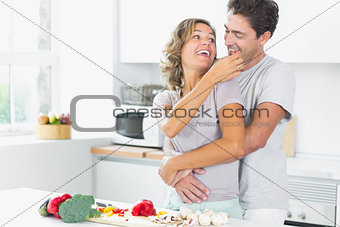 Wife jokingly feeding husband in kitchen