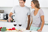 Husband pouring red wine in kitchen