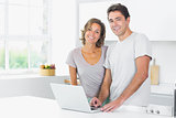 Couple standing in kitchen with laptop