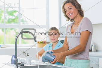 Happy mother and daughter doing the washing up