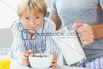 Father pouring milk for sons cereal