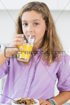 Girl having orange juice at breakfast