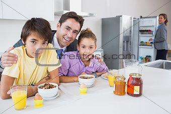 Smiling father and children having breakfast